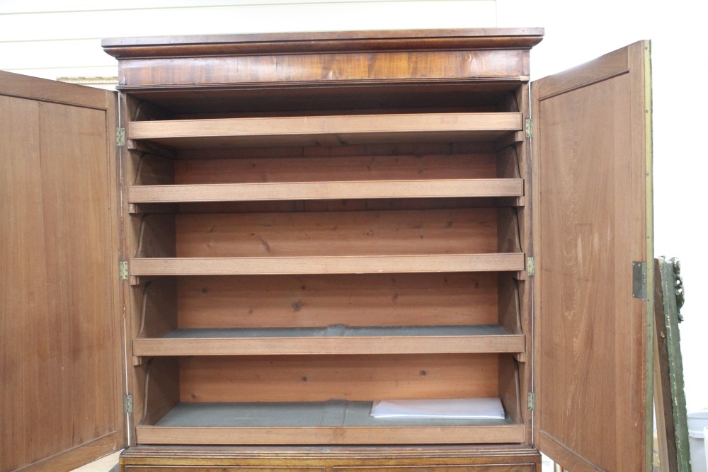 A Regency mahogany linen press with two doors enclosing five slides, two short drawers and two graduated long drawers, on swept bracket